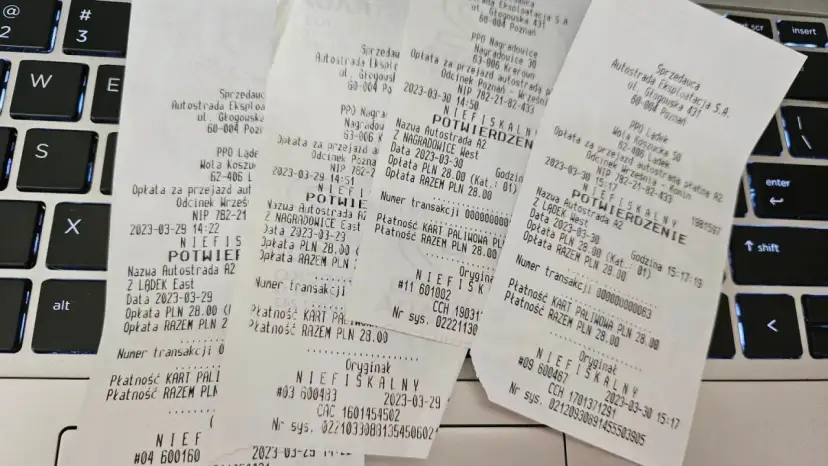 Paragon fiskalny z autostrady A2 na klawiaturze laptopa.