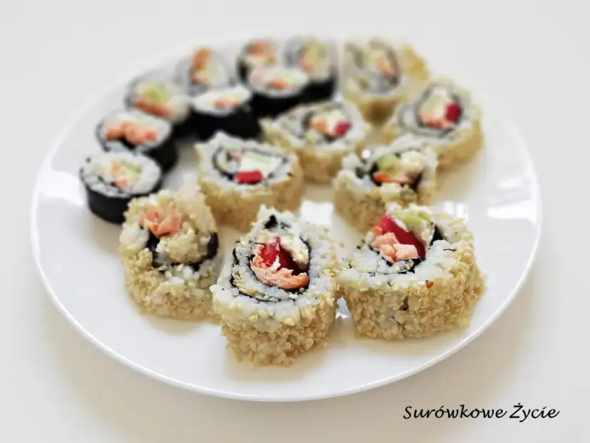 Talerz pełen sushi uramaki z łososiem, awokado i papryką, posypane sezamem. Pyszne i kolorowe rolki.