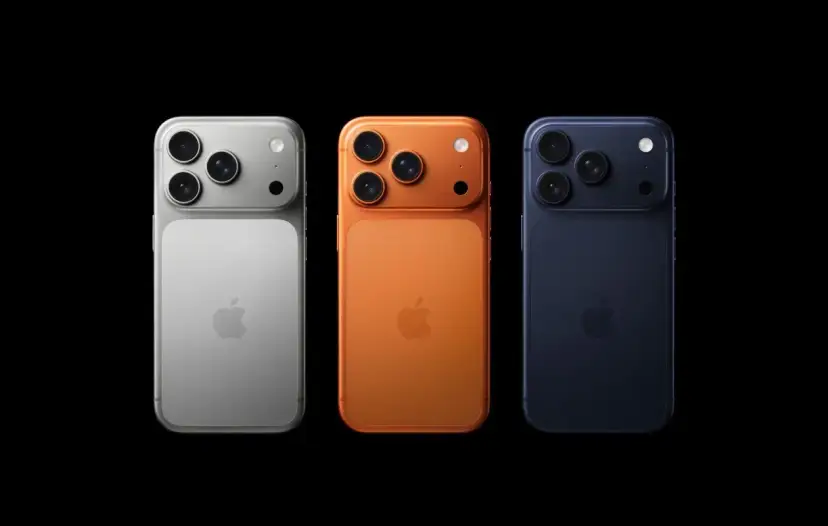 Trzy telefony iPhone w kolorach srebrnym, pomarańczowym i granatowym, z potrójnymi aparatami. Wyglądają jak przyszłe modele, może nawet iPhone 18.