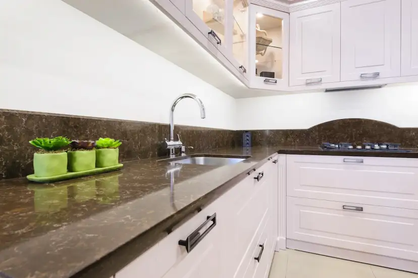 Nowoczesna kuchnia z białymi meblami, brązowym blatem i zlewozmywakiem.