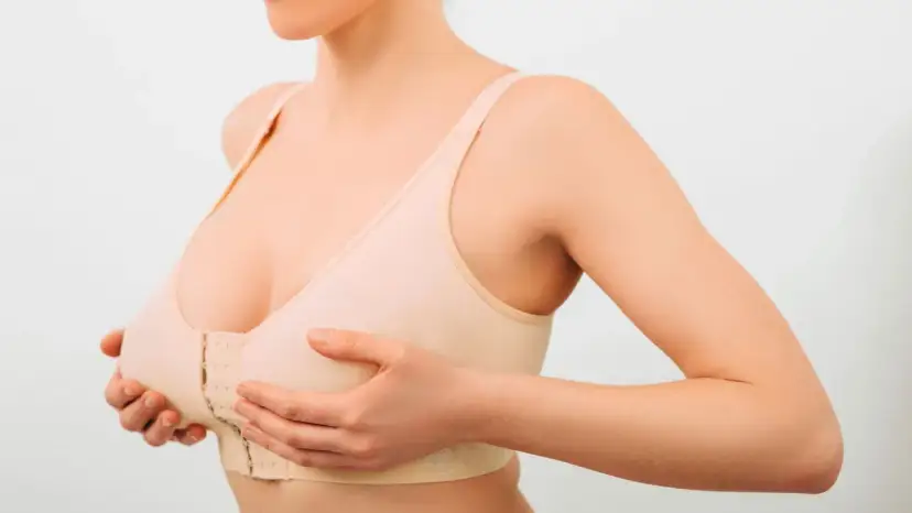 Kobieta w beżowym biustonoszu z zapięciem z przodu, dotykająca piersi.