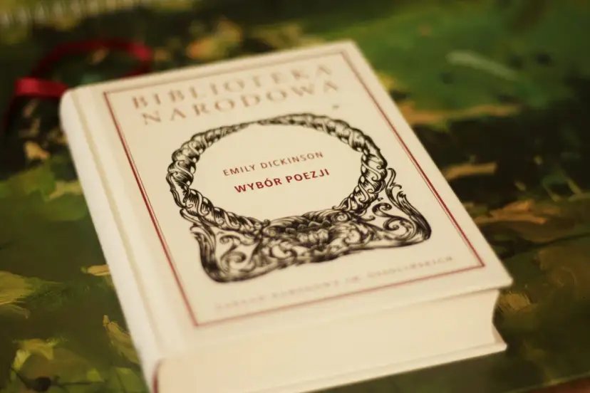 Biała księga z napisem "Emily Dickinson Wybór Poezji" w ozdobnej ramce.