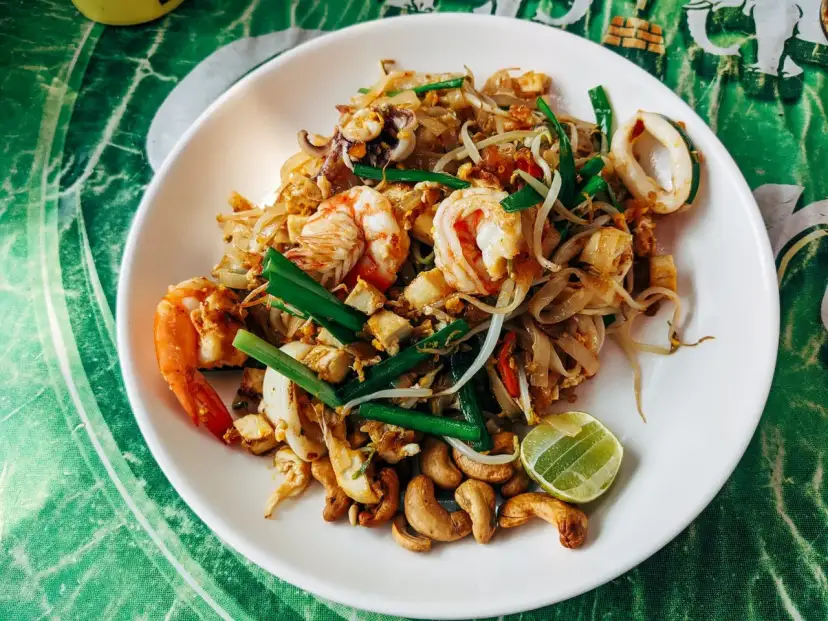 Pad thai z krewetkami, kalmarami, kiełkami i orzechami nerkowca. Widać też kawałek limonki, idealne pad thai składniki.