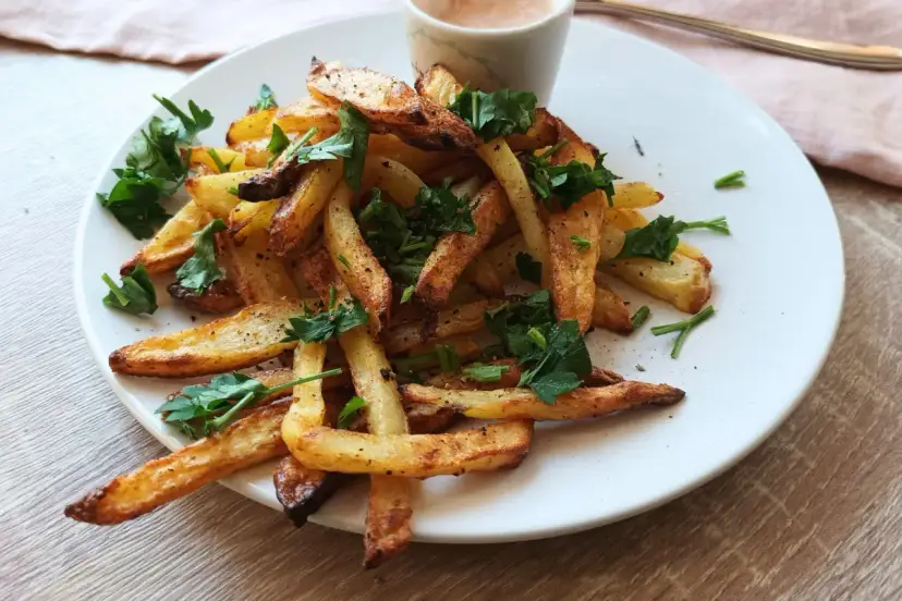 Złociste frytki z airfryera, posypane natką pietruszki. Idealne, gdy chcesz wiedzieć, jak zrobić frytki w airfryer.