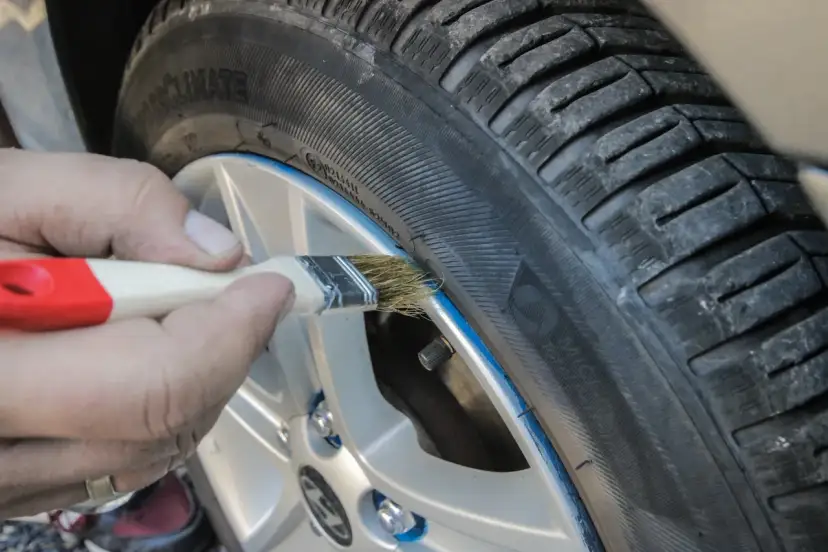 Ręka pędzlem maluje niebieską linię na oponie, nadając jej nowy wygląd. To nie jest zwykła guma w sprayu, to precyzyjne malowanie!