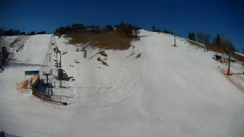 Słoneczny dzień na olczańskim wierchu. Stoki narciarskie, kolejka krzesełkowa i kilka budynków na szczycie.