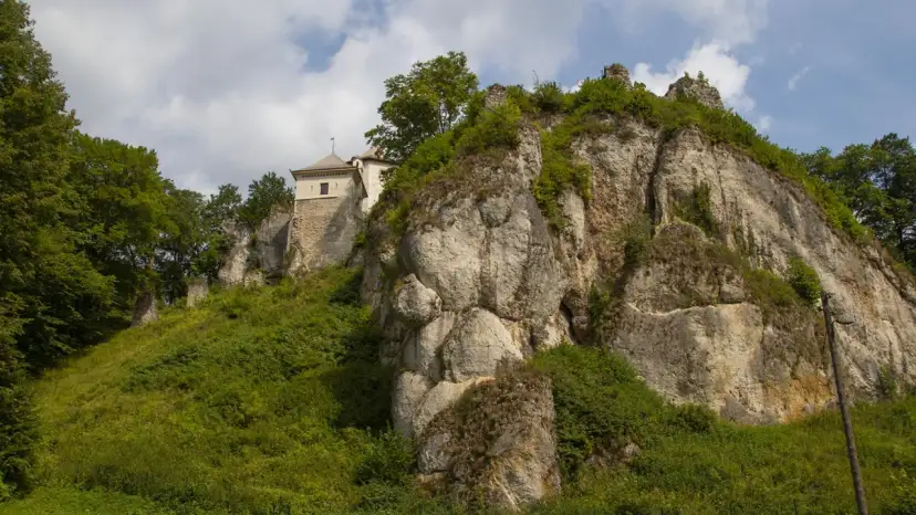 Zamek w Ojcowie góruje nad wapiennymi skałami, otoczony bujną zielenią.