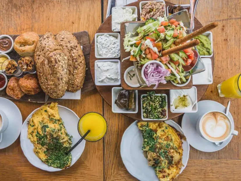 Obfite śródziemnomorskie śniadanie: omlety, pieczywo, sałatka, dipy i kawa. Idealny początek dnia.