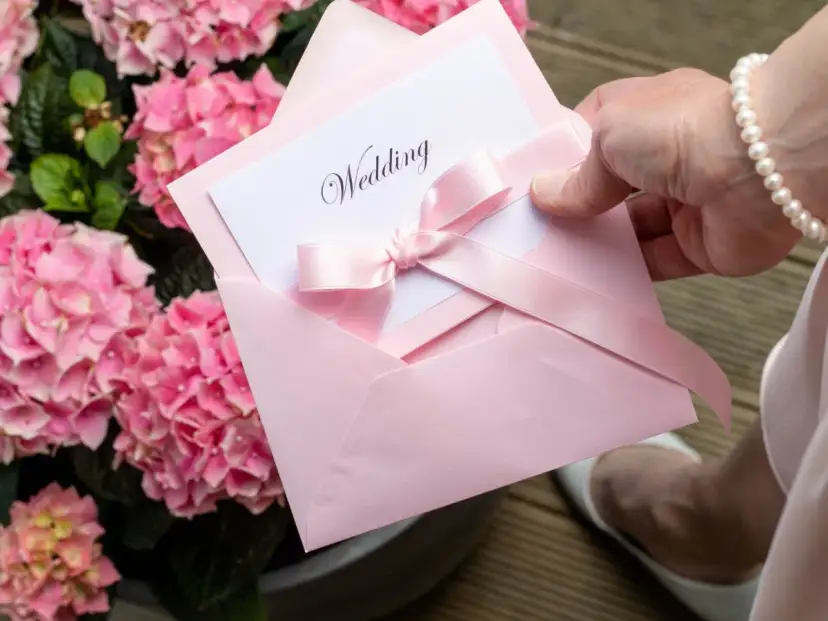 Różowa koperta z zaproszeniem na ślub. Jak grzecznie odmówić zaproszenia przykłady, gdy nie możesz uczestniczyć.