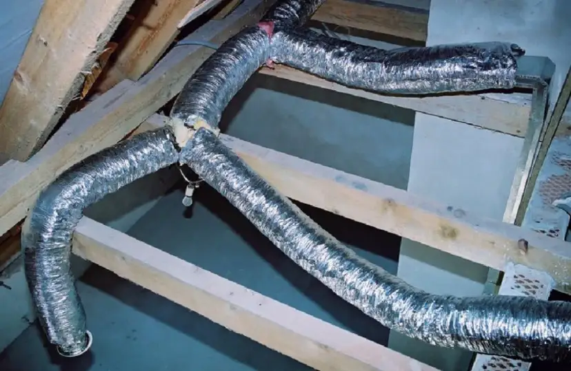 System rozprowadzenia ciepła z kominka: elastyczne, aluminiowe rury wentylacyjne prowadzone przez drewnianą konstrukcję poddasza.