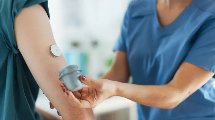 Lekarz od chorób metabolicznych pomaga pacjentowi z glukometrem na ramieniu.