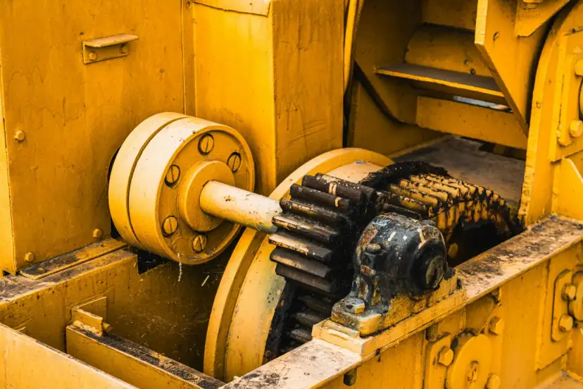 Żółta maszyna z zębatkami, gdzie różne rodzaje smarów chronią mechanizm przed zużyciem.