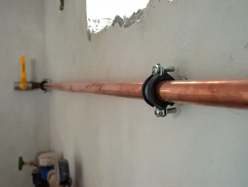 Miedziana rura gazowa, zamocowana obejmą. W tle żółty zawór. Jaka średnica rury do gazu ziemnego?