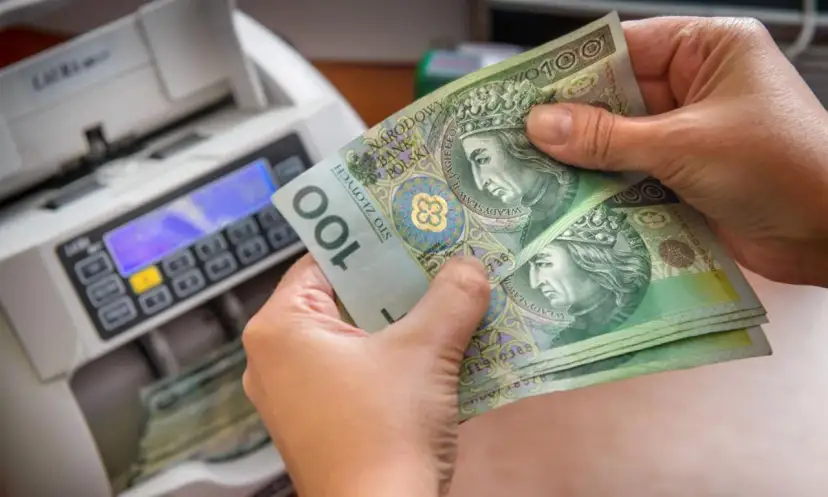 Ręce trzymają banknoty 100 zł obok licznika pieniędzy. Czy przy wcześniejszej spłacie kredytu należy się zwrot odsetek?