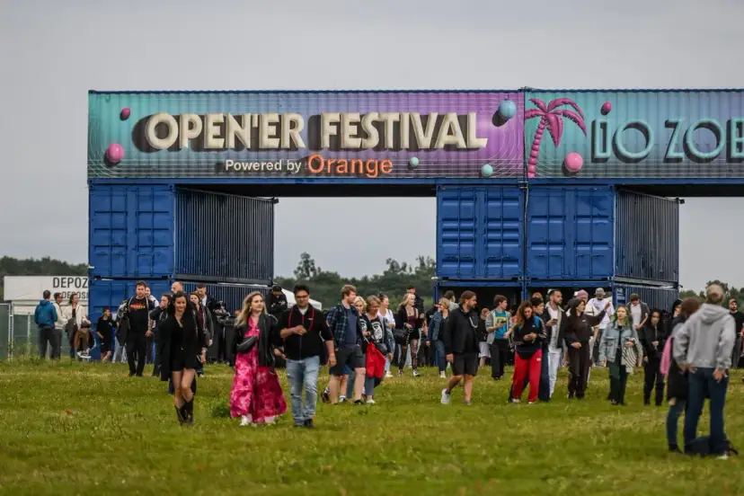 Tłum ludzi wchodzi na teren festiwalu. Nad nimi brama z napisem "OPEN'ER FESTIVAL". Kto będzie następny?