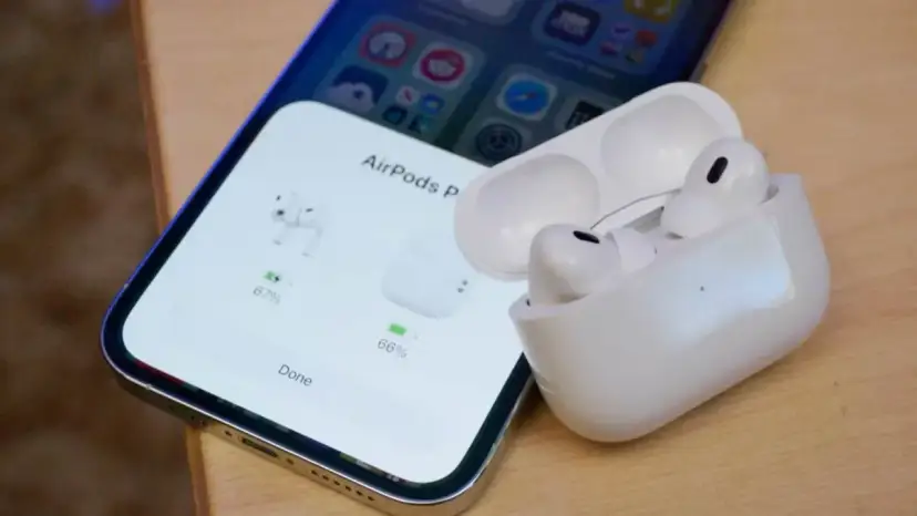 iPhone z otwartym etui AirPods Pro, pokazującym stan naładowania słuchawek.