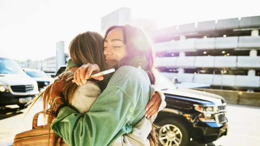 Dwie kobiety obejmują się czule, jedna z nich trzyma w dłoni telefon. To przeprosiny prosto z serca, pełne emocji i ulgi po długim rozstaniu.