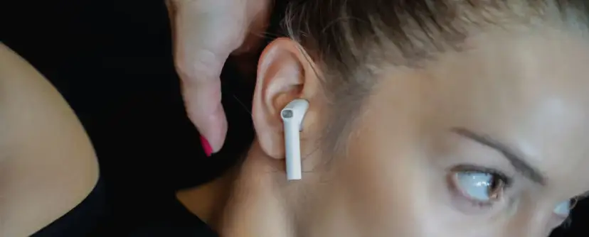 Zbliżenie na ucho kobiety z białymi słuchawkami bezprzewodowymi.