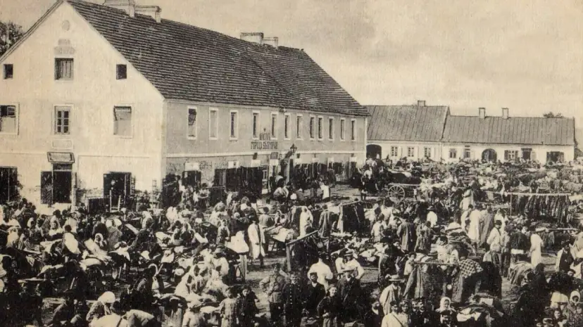 Tłum ludzi na targu w Biłgoraju, jakby żywcem wyjęty z legendy o tym mieście. W tle budynki i stragany.