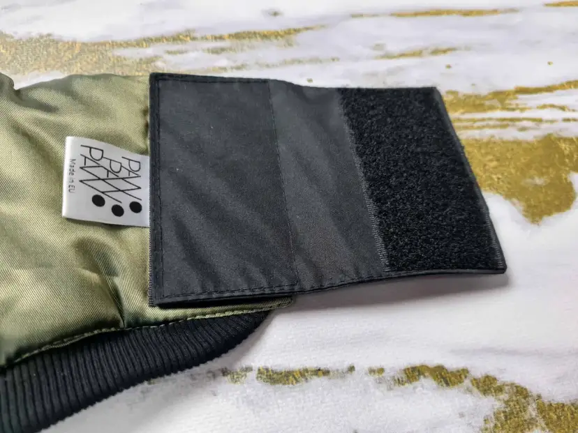 Fragment kurtki z naszytym rzepem, pokazujący, jak poszerzyć kurtkę. Metka "PAW Made in EU".