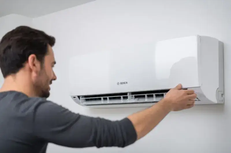 Mężczyzna regulujący klimatyzator ścienny w mieszkaniu
